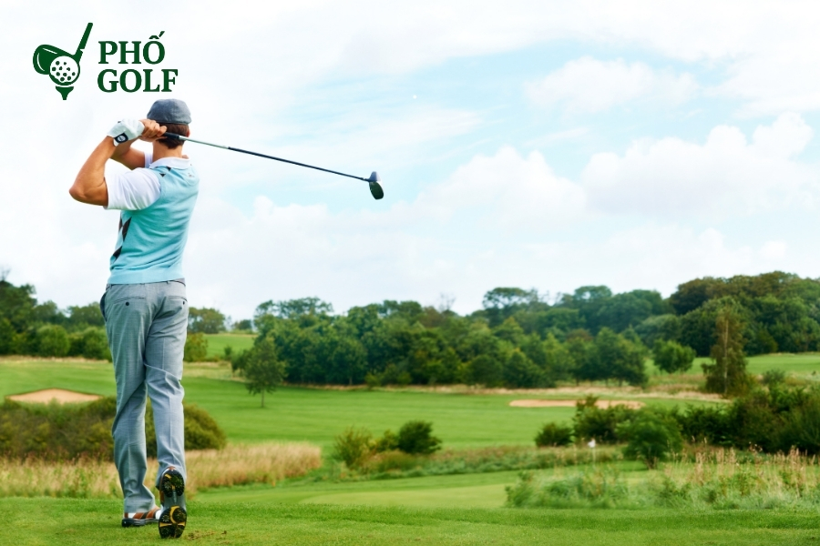 Cách đánh golf trên địa hình sườn dốc uphill và downhill Golfer chuẩn bị đánh bóng trên địa hình dốc lên, tay cầm gậy sắt, hướng mục tiêu nghiêng sang phải