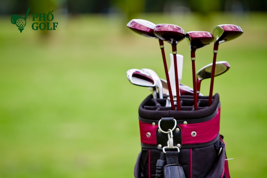 Cách đánh golf trên địa hình sườn dốc uphill và downhill Golfer đang chuẩn bị đánh bóng trên địa hình dốc xuống, tay cầm gậy ngắn, cơ thể nghiêng sang trái để điều chỉnh hướng cú đánh