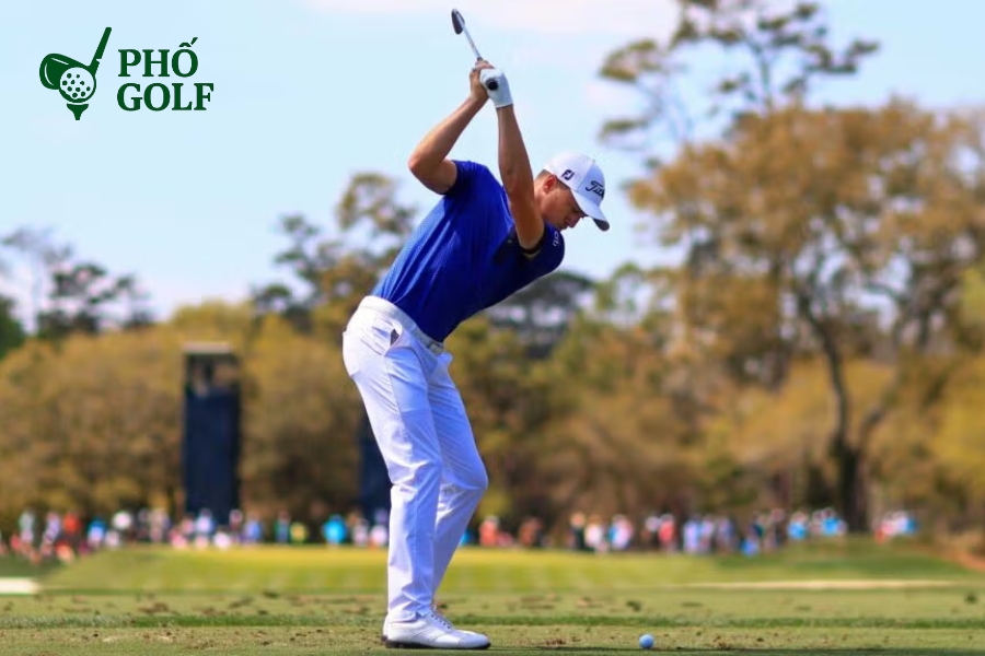 Hướng dẫn đánh gậy driver xa và thẳng cho người mới Golfer đang thực hiện động tác swing với cánh tay duỗi thẳng tạo vòng cung rộng, giữ khăn kẹp giữa cánh tay và ngực để duy trì độ rộng swing