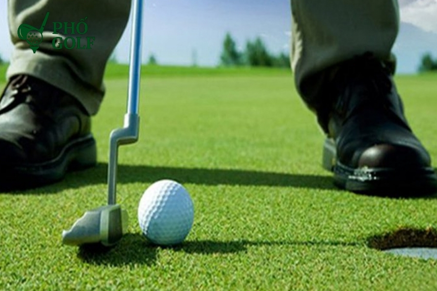 Hướng dẫn kỹ thuật putt golf giúp bạn tự tin ghi điểm Golfer thiết lập tư thế putt chuẩn, chân rộng bằng vai, tay và vai thả lỏng